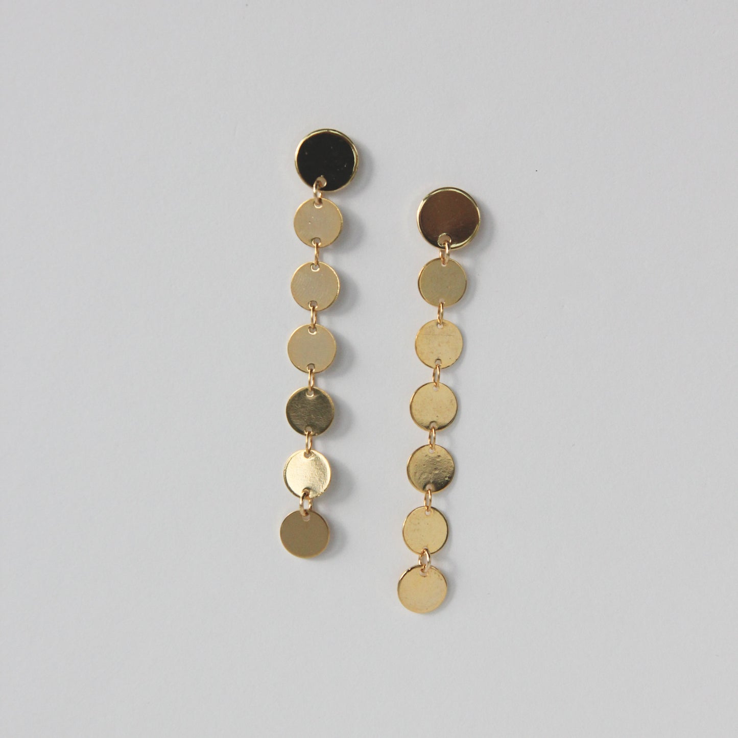 Pair of gold and black dangling earrings on a gray background