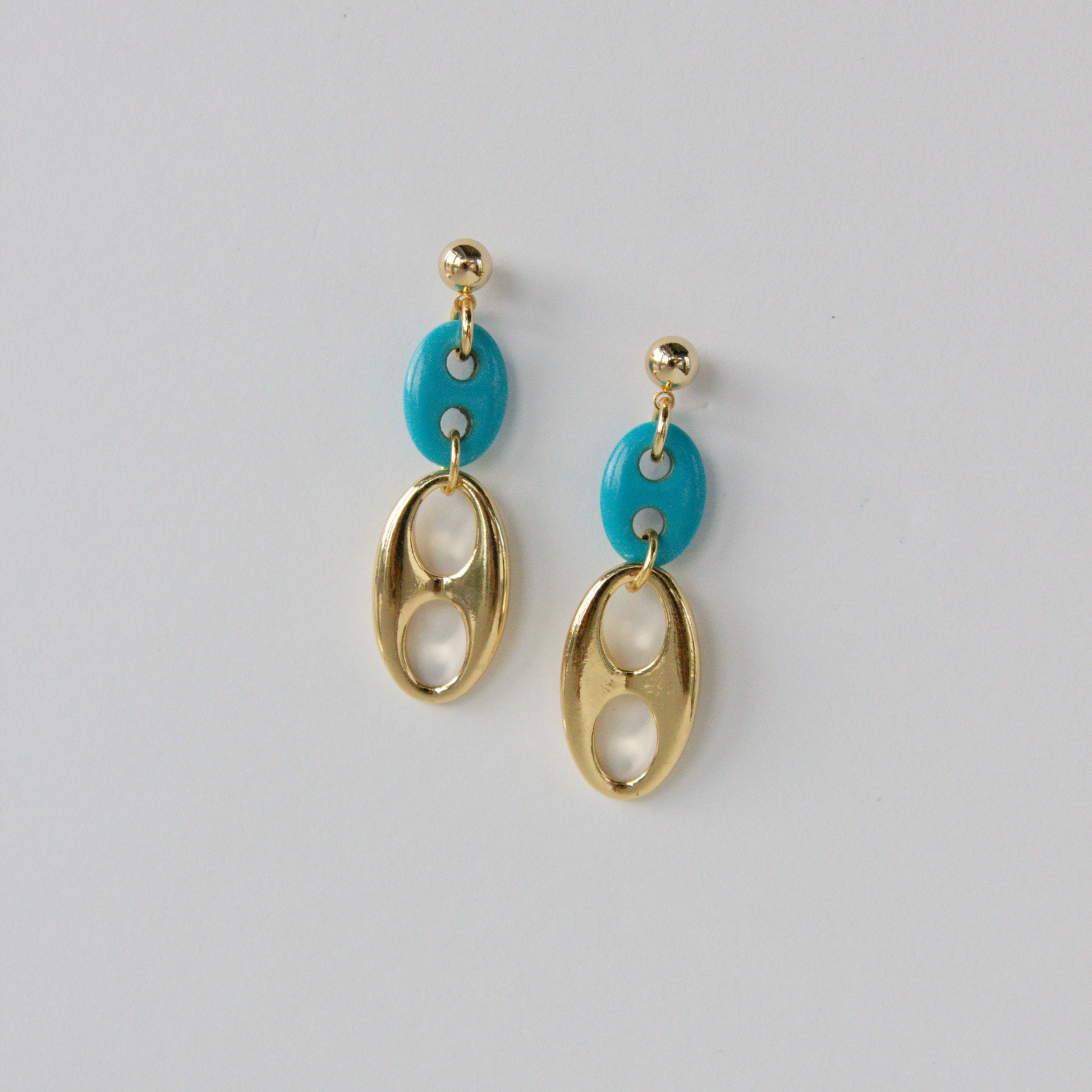 Gold and turquoise earrings on a light gray background