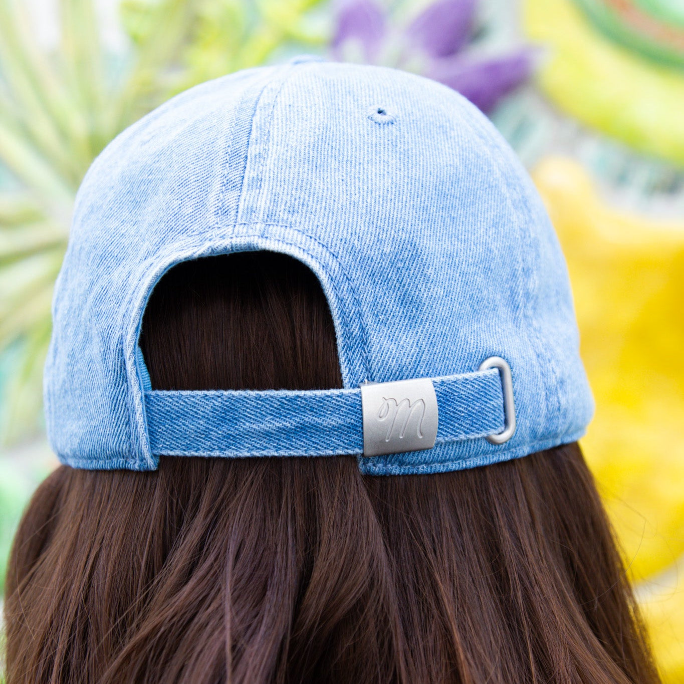 Person wearing a light blue denim cap with a blurred colorful background