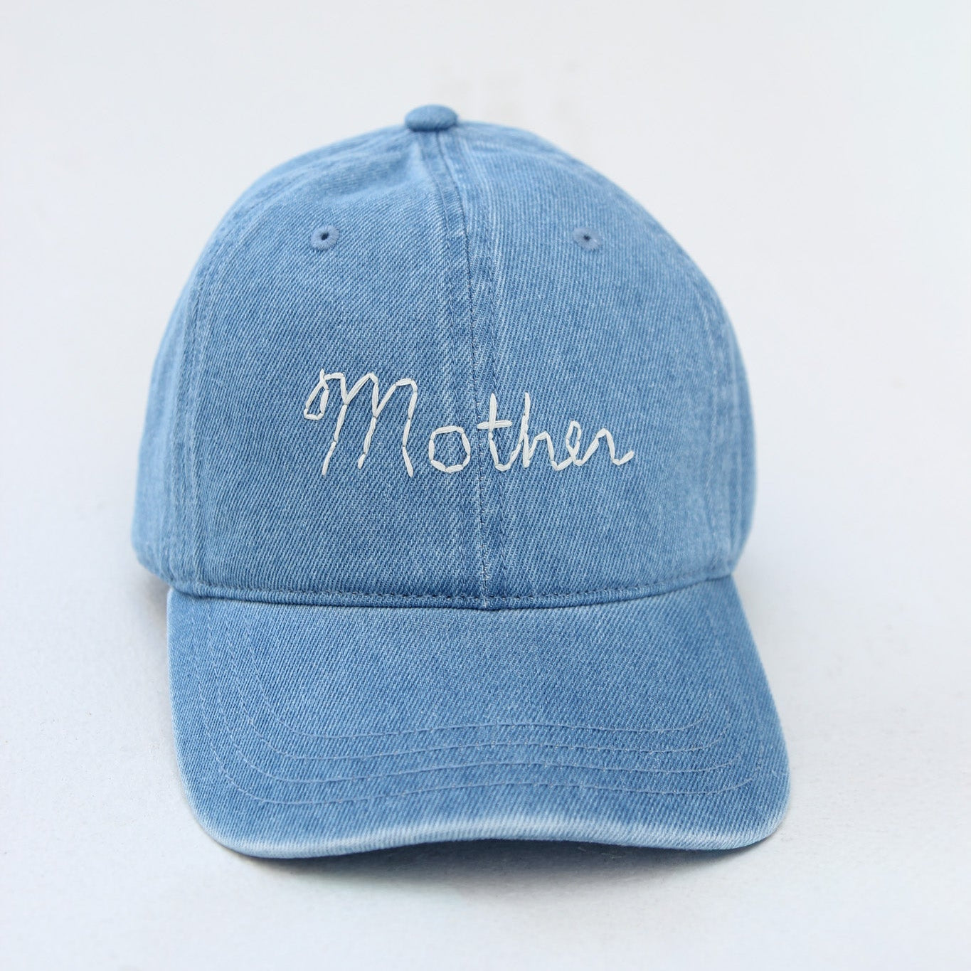 Blue denim cap with 'Mother' embroidery on a white background