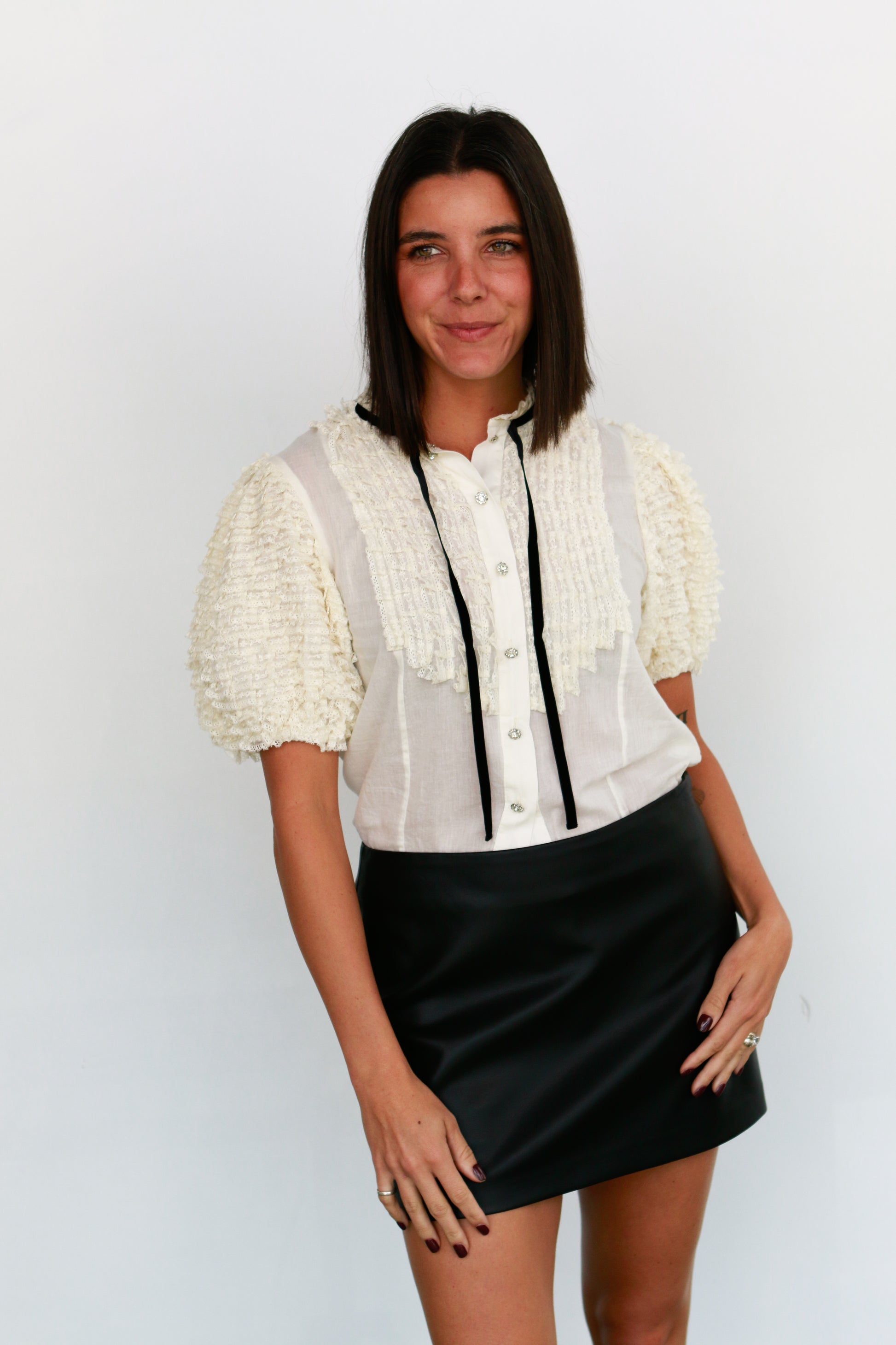 Woman wearing a white blouse with puff sleeves and a black skirt against a plain background love the label oceane blouse